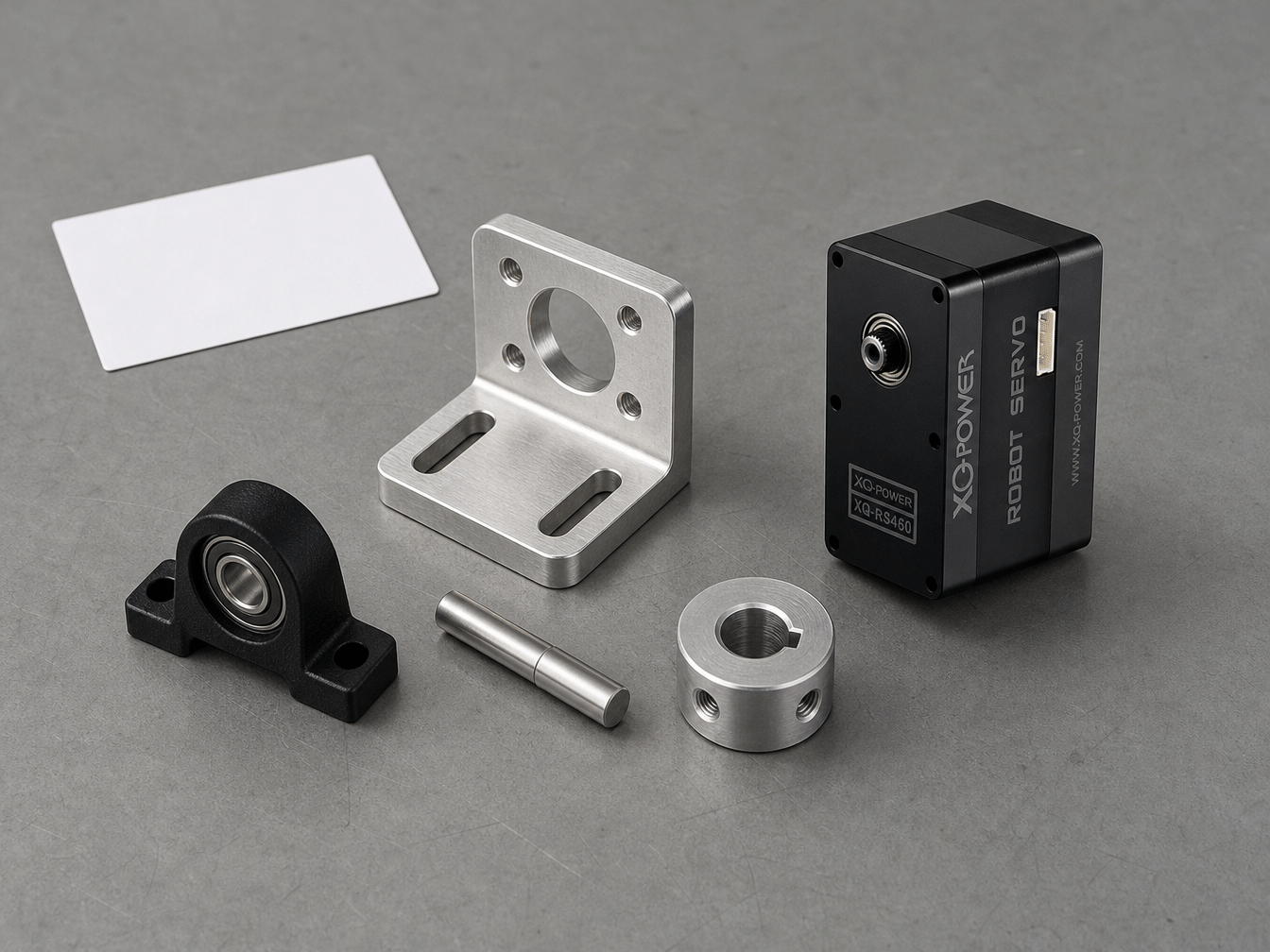 XQ-POWER RS460 robot servo beside an L-shaped aluminium mounting bracket, a polished steel shaft, a pillow block ball bearing and a keyed shaft collar on an engineering bench