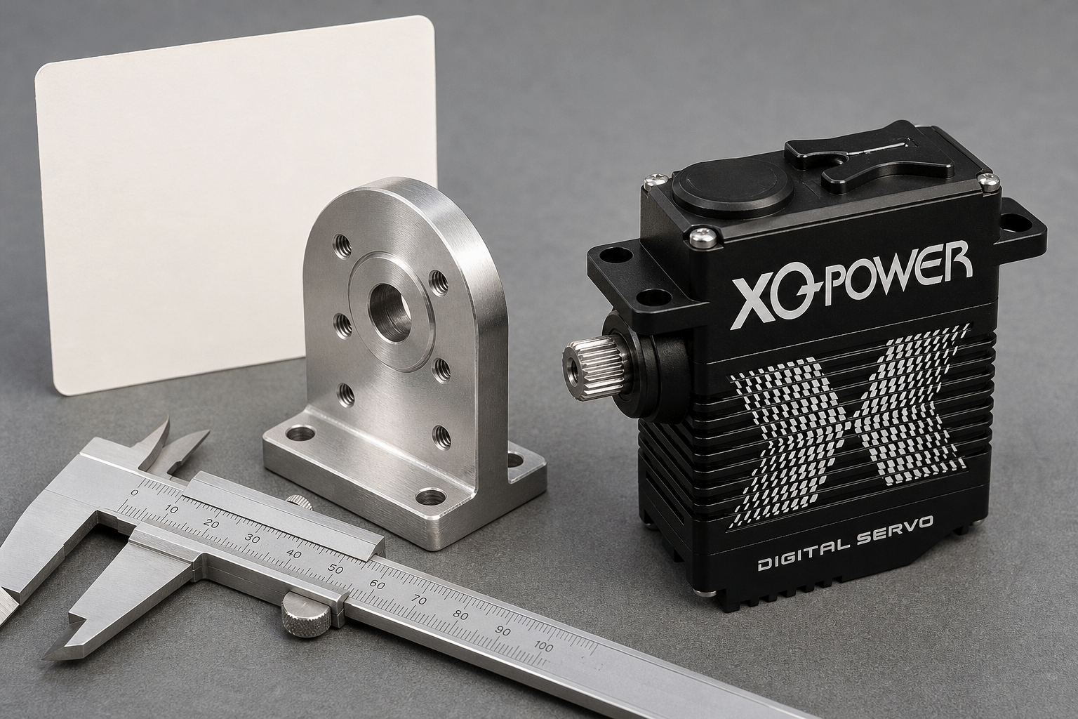XQ-POWER digital servo with a splined output shaft, shown beside an L-shaped mounting bracket and vernier calipers on a workbench